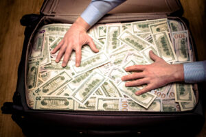 man holding hands on a suitcase with US currency