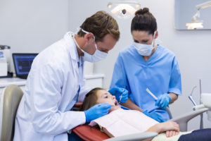 Dentist examining a young patient with tools in dental clinic